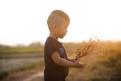 Close-up of girl standing on field against sky