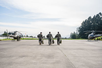 Military men at airport runway against sky