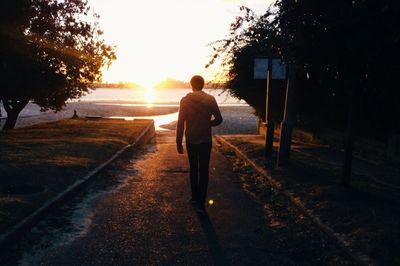 Rear view of man standing on road against sky