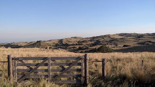 Fence on field against clear sky