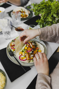 Person wrapping mexican tortilla with various toppings