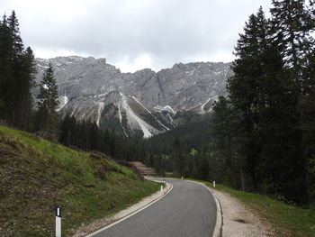 Road amidst trees and mountains against sky