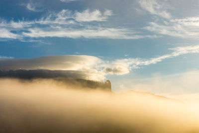 Low angle view of sunlight streaming through clouds