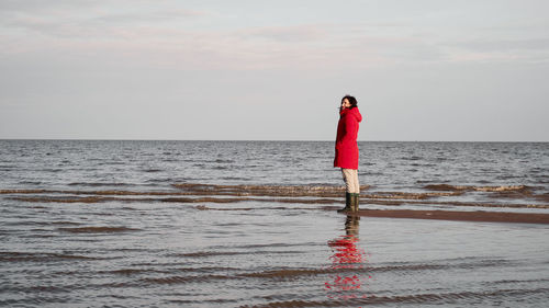 Woman standing on sea shore against sky