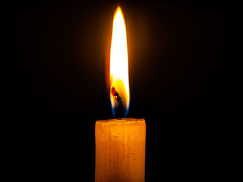 Close-up of burning candle against black background