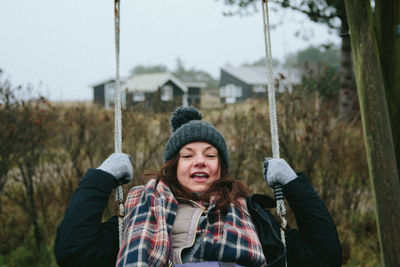 Portrait of woman swinging against sky