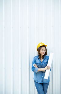 Portrait of young woman standing against wall