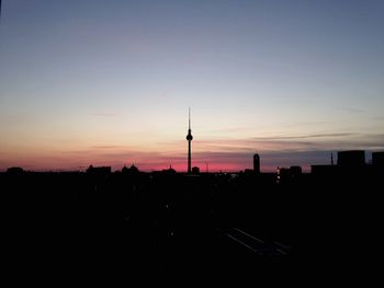 Silhouette cityscape against sky at sunset