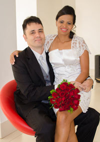 Portrait of smiling young couple with red roses on seat