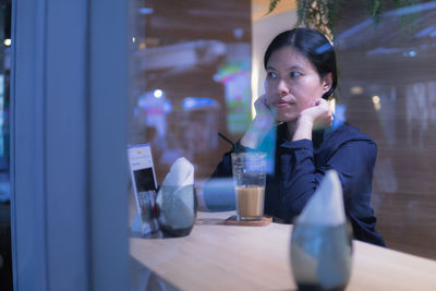 Woman looking away by coffee glass on table