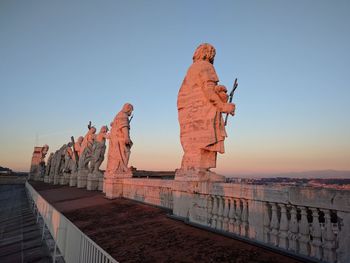 Statues on building against sky during sunset