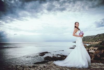 Woman standing on field by sea against sky