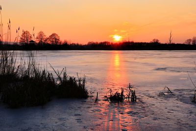 Scenic view of lake against orange sky during sunset