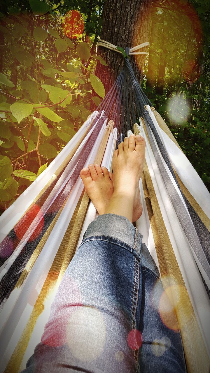 LOW SECTION OF WOMAN RELAXING IN HAMMOCK