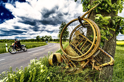 Bicycle on road amidst field against sky