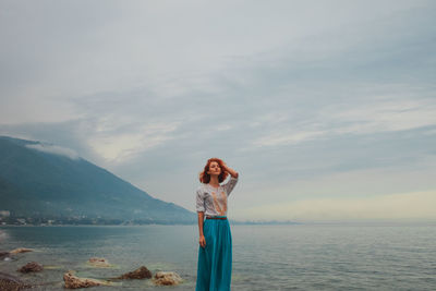 Portrait of woman standing by sea against sky