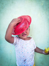 Girl wearing hat standing against wall