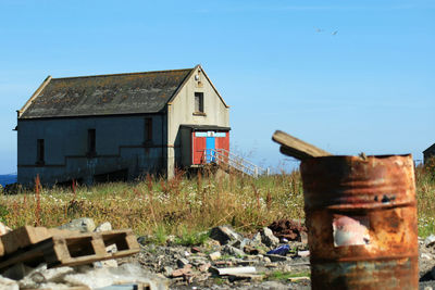 Abandoned house on field against clear blue sky