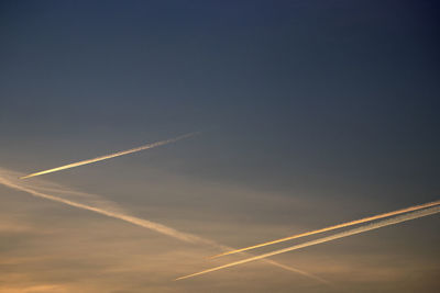 Low angle view of vapor trail in sky during sunset