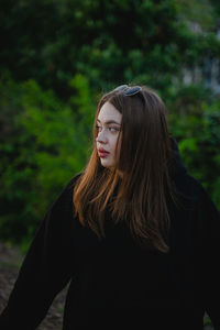 Young woman standing against trees