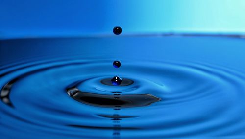 Close-up of drop splashing in blue water
