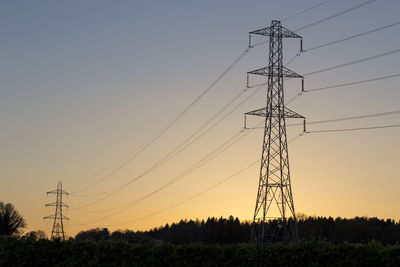 Low angle view of electricity pylon on field against clear sky