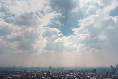 Aerial view of city buildings against cloudy sky