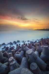 Scenic view of rocky beach against sky during sunset