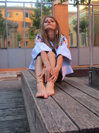 Full length of girl sitting on wood