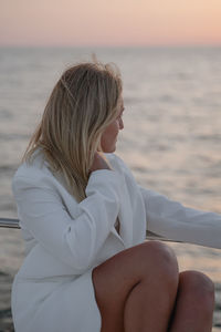 Side view of woman sitting at beach