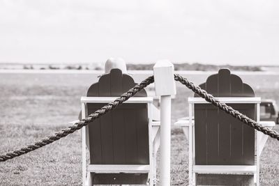 Rear view of men standing on railing against sea