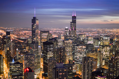 Illuminated cityscape against sky during sunset