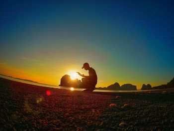 Silhouette man on field against sky during sunset