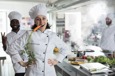 Female chef biting carrot in commercial kitchen