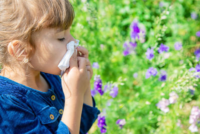 Side view of young woman blowing flowers