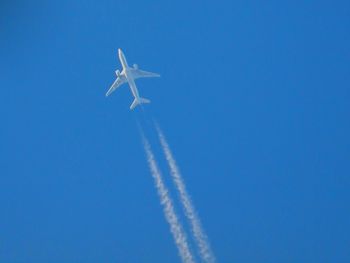 Low angle view of airplane flying against clear blue sky