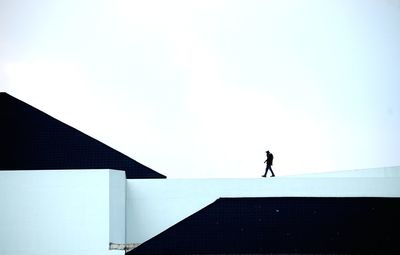 Silhouette man standing against clear sky, siluet worker up of building like on the mountain 