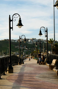 Street lights on footpath against sky