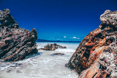 Rock formations in sea against blue sky