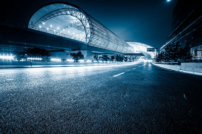 Surface level of road on illuminated bridge against sky in city