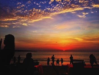 Silhouette people on beach at sunset