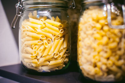 Close-up of pasta in jars on shelf in kitchen at home