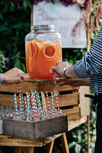 Midsection of man taking lemonade from jar