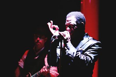 Full length of man playing guitar against black background