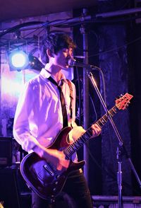 Teenage boy playing guitar at music concert