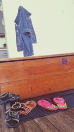 Close-up of shoes on wooden table against wall