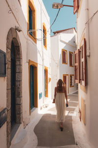 Rear view of woman walking on street amidst buildings