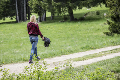 Rear view of woman with dog walking on grassland