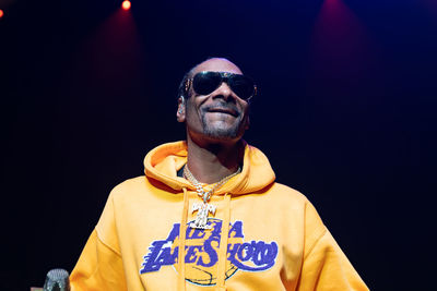 Portrait of young man wearing sunglasses standing against black background