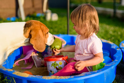 Side view of girl playing with dog